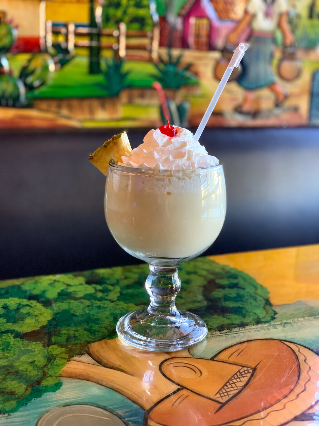 Creamy drink topped with whipped cream, a cherry and pineapple