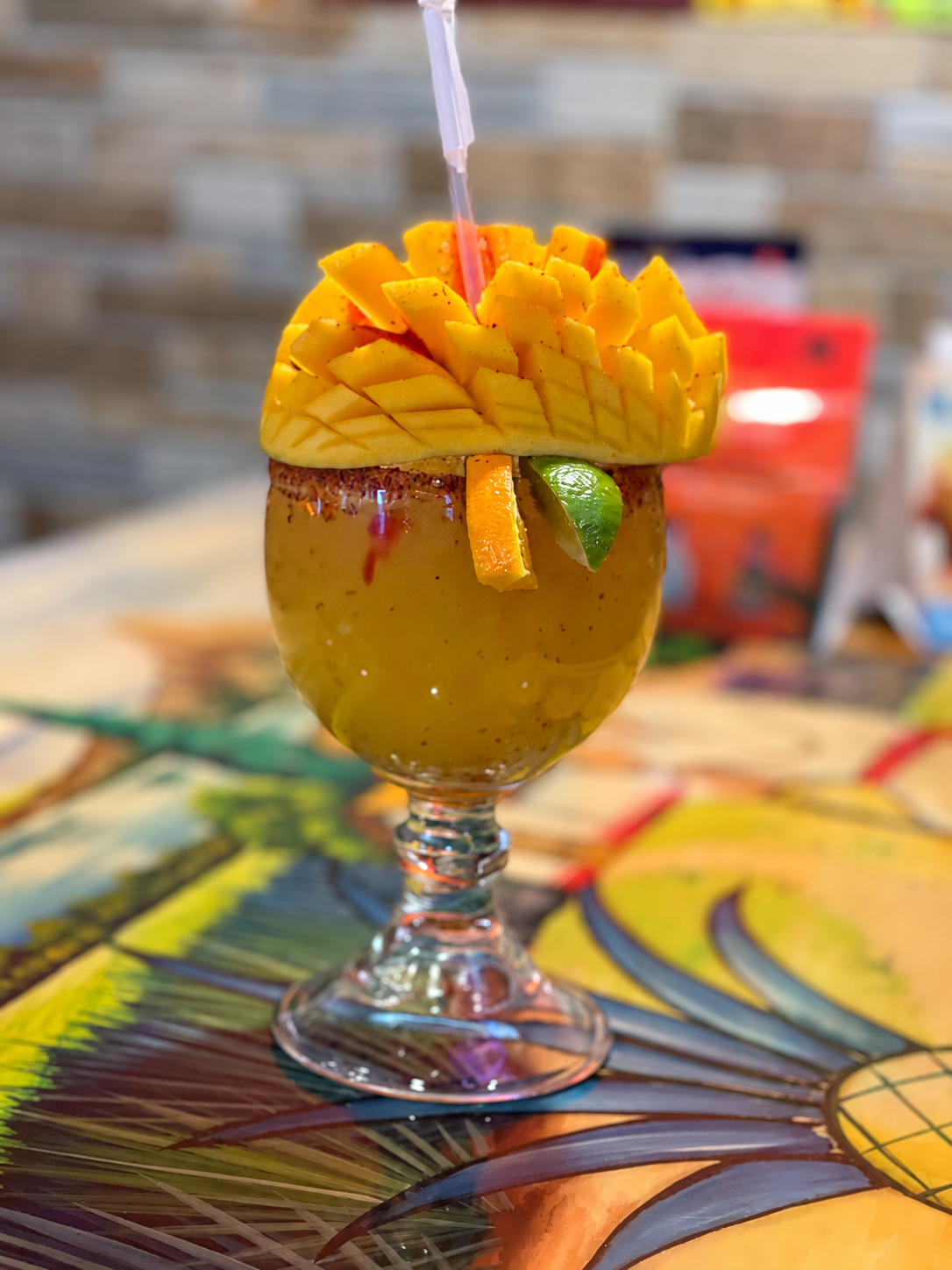 Mango-colored margarita topped with a fan of mango slices and citrus