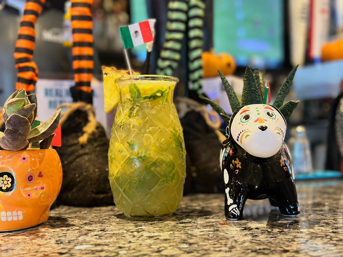 Tropical drink in a pineapple-shaped glass with a Mexican flag at the bar