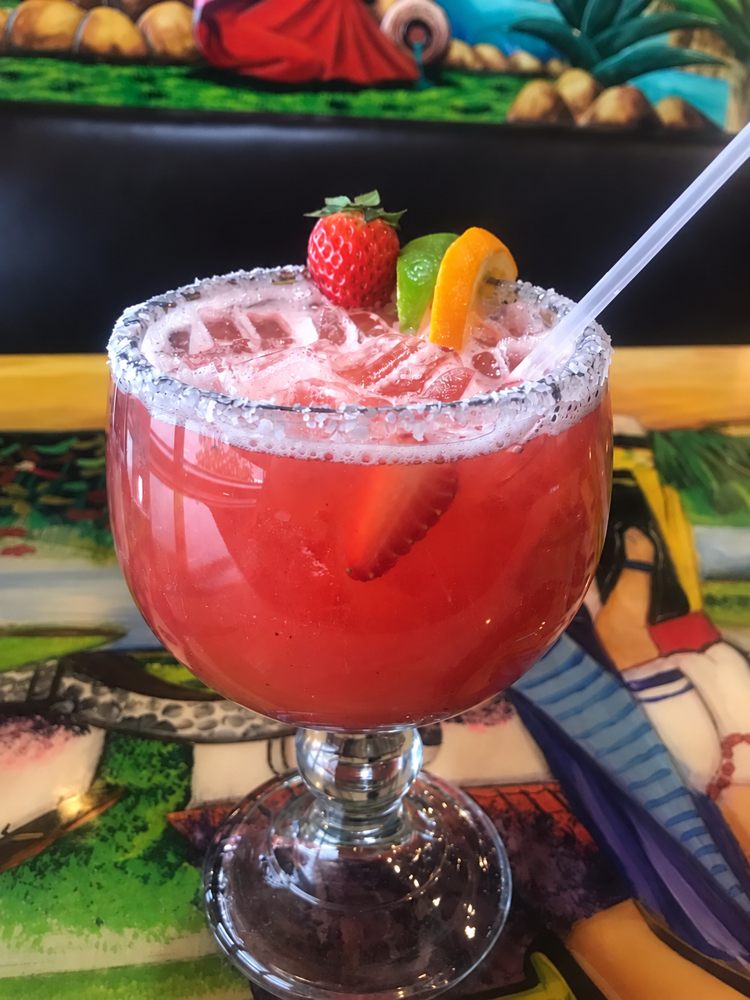 Pink margarita with a salted rim, strawberry and citrus garnish