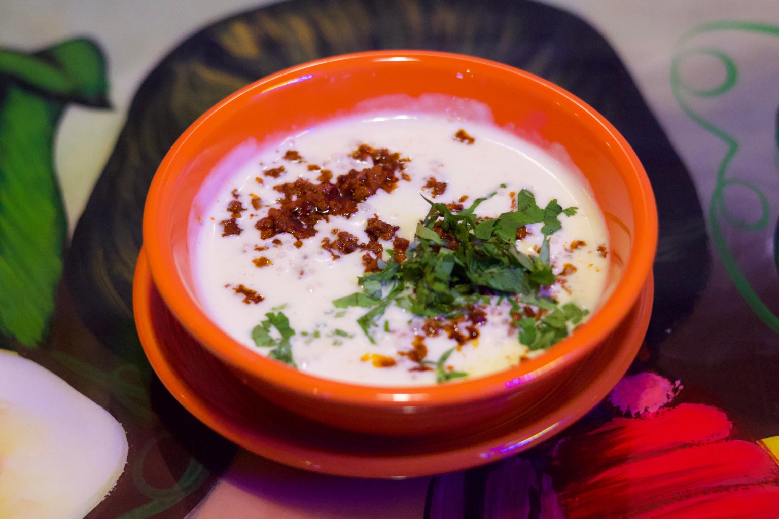 A bowl of creamy queso topped with crumbled meat and herbs
