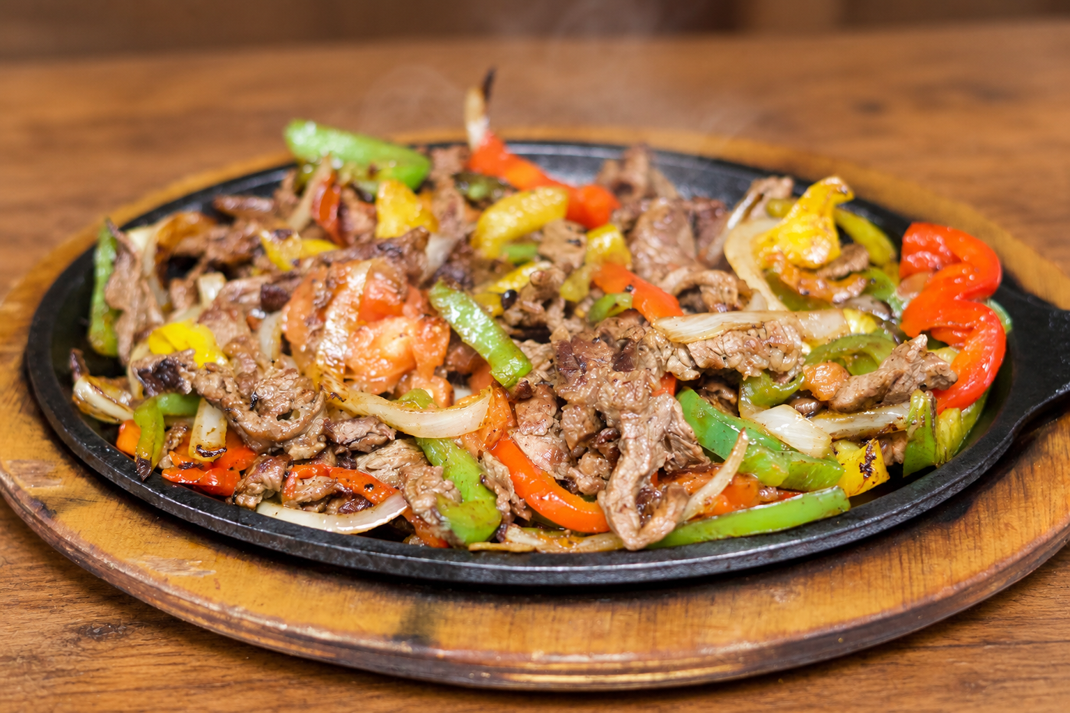 A sizzling fajita platter on a warm wood table